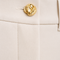 Close-up of AURA ivory tailored trousers featuring a sculpted gold waist button and refined tailoring by Modella