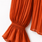 Close-up of AURA orange pleated blouse by Modella showing the finely pleated sleeve and flared ruffle cuff detail