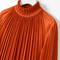 Close-up of AURA orange pleated blouse by Modella showing the fine pleating and ruffled high-neck collar detail