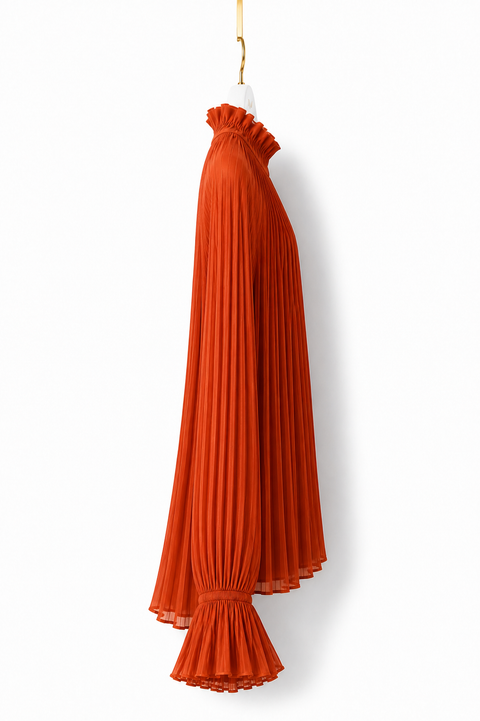 Side view of AURA orange pleated blouse by Modella featuring fine pleating, a ruffled high neckline and flared ruffle cuff