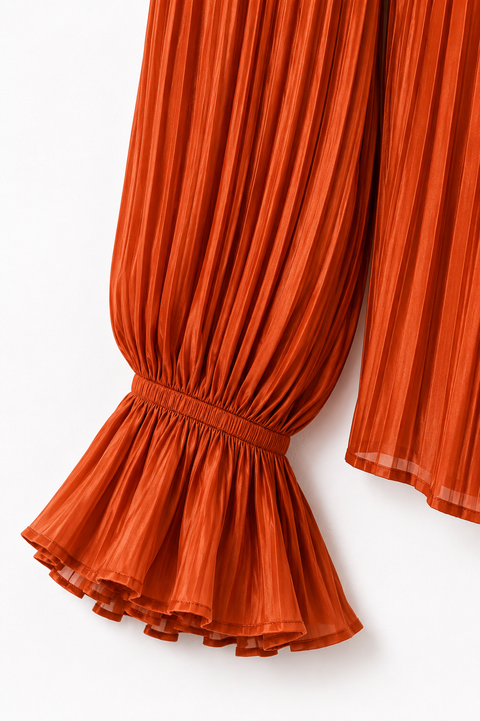 Close-up of the orange pleated blouse from the AURA women’s ivory three-piece tailored suit by Modella showing the gathered sleeve and flared pleated cuff