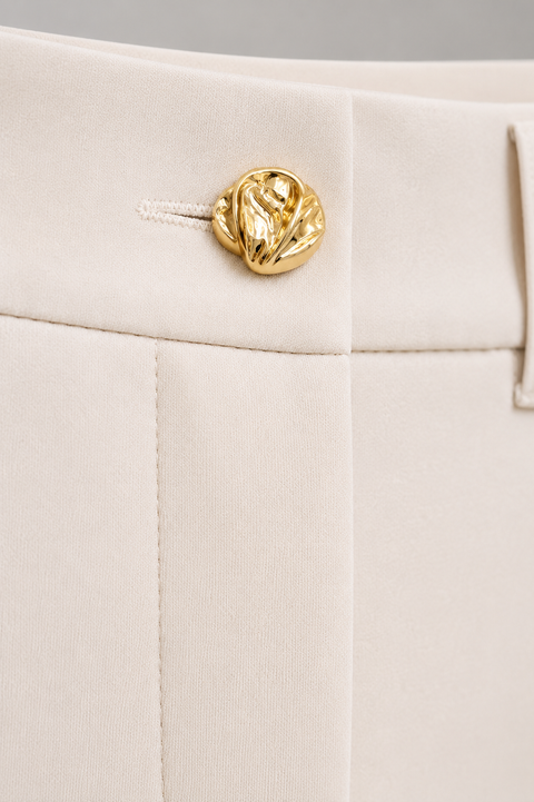 Close-up of the AURA ivory three-piece suit trousers by Modella showing the gold waist button, tailored waistband and ivory fabric