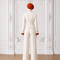 Back view of AURA women’s ivory three-piece tailored suit by Modella showing the fitted ivory jacket, wide-leg trousers and orange pleated blouse cuffs