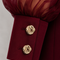 Close-up of EVE burgundy jumpsuit by Modella showing the sheer gathered sleeve, structured cuff and gold button detailing