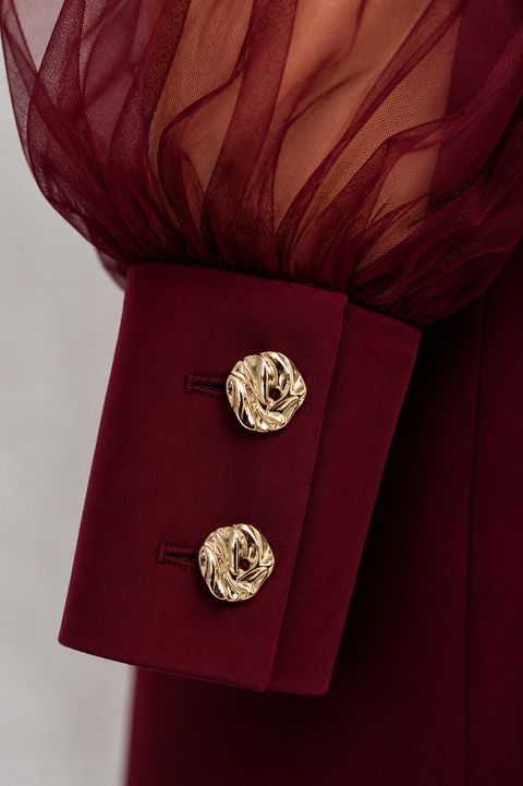 Close-up of EVE burgundy jumpsuit by Modella showing the sheer gathered sleeve, structured cuff and gold button detailing